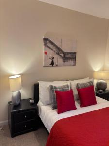 a bedroom with a bed with red pillows and a painting at AB11 Apartments - Portland Street in Aberdeen