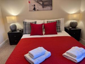 a bedroom with a red bed with two towels on it at AB11 Apartments - Portland Street in Aberdeen
