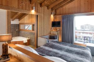 a bedroom with a bed and a tub and a television at Hôtel Chalet & Spa Le Delta in Le Grand-Bornand