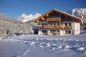 uma casa na neve com montanhas ao fundo em Appartement Sonnengarten em Ramsau am Dachstein