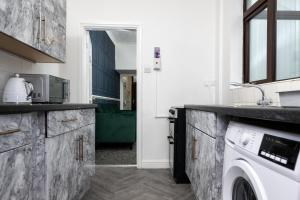a kitchen with a sink and a washing machine at Superior 4-Bedroom Home ideal for families, Contractors and Relocations in Stoke on Trent +14 photos