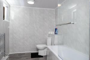 a white bathroom with a toilet and a bath tub at Superior 4-Bedroom Home ideal for families, Contractors and Relocations in Stoke on Trent