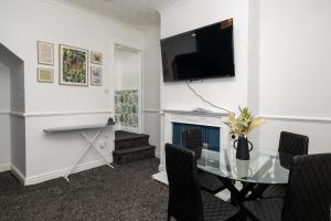 a dining room with a glass table and a television at Superior 4-Bedroom Home ideal for families, Contractors and Relocations in Stoke on Trent