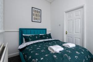 a bedroom with a blue bed with towels on it at Superior 4-Bedroom Home ideal for families, Contractors and Relocations in Stoke on Trent