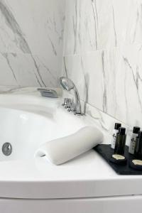 a white bathroom sink with a toothbrush holder next to it at Hôtel Le domaine de Montmorency in Montmorency