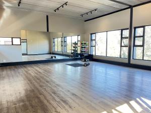 an empty room with a wooden floor and windows at 13A Elizabeth Place - Beautiful self catering 2 bedroom unit next to Kyalami Racetrack with free WiFi - swimming pool gym and restaurant - Perfect for a small family in Midrand Waterfall in Kyalami