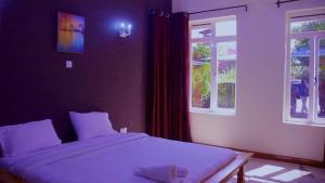 a bedroom with a white bed and two windows at La Casa Savanna in Naivasha