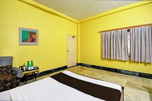 a yellow room with a bed and a chair at Hotel O Arati House in Kolkata