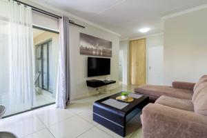 un salon avec un canapé et une télévision dans l'établissement Buckingham Palace 2 Bed 2 Bath, à Midrand