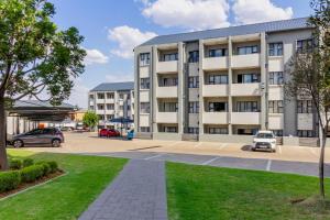 un immeuble d'appartements avec des voitures garées dans un parking dans l'établissement Buckingham Palace 2 Bed 2 Bath, à Midrand