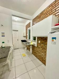 a kitchen with white cabinets and a brick wall at Chalés Santo Antônio em Flecheiras in Flecheiras
