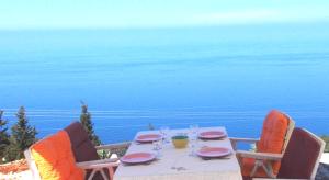 a table with plates and glasses on top of the ocean at Porto Katsiki Blu in Athani