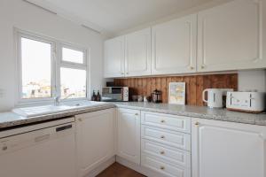 a white kitchen with white cabinets and a window at Quiet Comfy Riverside Lodge - Club Casita in Christchurch