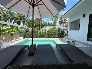 a swimming pool with two chairs and an umbrella at Aonang nine poolvilla resort in Ao Nang 