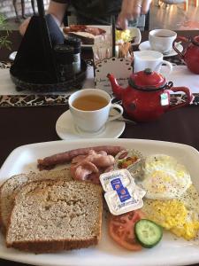 a plate of breakfast food with eggs and toast and a cup of tea at Ansta Farmhouse Self Catering Camping Nursery in Outjo