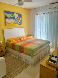 ein Schlafzimmer mit einem Bett mit einer bunten Decke in der Unterkunft Guaratuba 2 sobrado cinematográfico próximo da praia in Bertioga