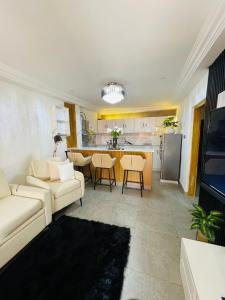 a living room with a white couch and a kitchen at Comfort et style au coeur de la ville in Lomé