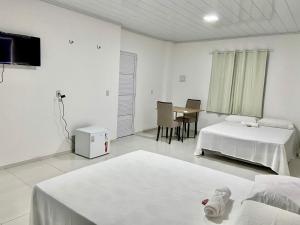 a white room with two beds and a table at Hospedaria Dona Santa in Pinheiro