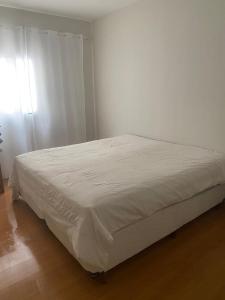 a white bed in a bedroom with a white wall at Casa São João del Rei Proximo a Tiradentes in São João del Rei