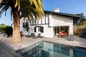 a house with a swimming pool and a palm tree at Magnifique maison basque avec piscine 8 pers- Biarritz in Biarritz