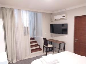 a hotel room with a bed and a desk and a television at Akraios Guesthouse Beautiful Stone House in Konak in Konak