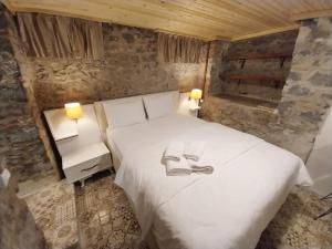 a bedroom with a bed with two shoes on it at Akraios Guesthouse Beautiful Stone House in Konak in Konak