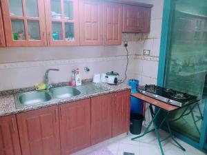 una cucina con armadi rossi, lavandino e piano cottura di shared bathroom room a Al Ain