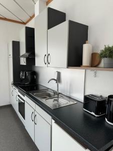 a kitchen with white cabinets and a black counter top at Ferienhaus Alte Bank in Göcklingen in Göcklingen +17 photos