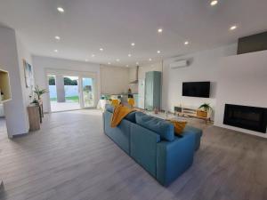 Una sala de estar con un sofá azul y un televisor en Casa Calma, en Conil de la Frontera
