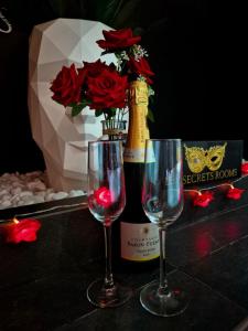 zwei Weingläser neben einer Flasche Wein in der Unterkunft Les Secrets Rooms in Hagondange