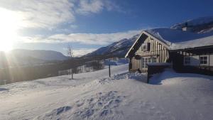 a snow covered building with the sun in the background at Einsetlie by Norgesbooking - cabin by Hallingskarvet in Hovet