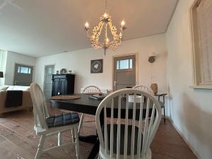 una sala da pranzo con tavolo, sedie e lampadario di T'hûs bed & breakfast a Katlijk