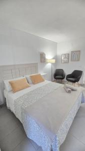een slaapkamer met een groot bed en twee stoelen bij Benalmadena Minerva Apartamento con gran piscina in Benalmádena +30 foto's