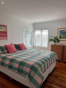a bedroom with a bed with a plaid blanket at The City Cottage in Auckland