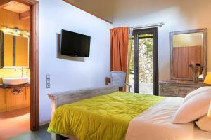 ein Schlafzimmer mit einem Bett mit Fernseher und einem Badezimmer in der Unterkunft Villa Acqua, a luxury villa with private pool, 10 mins drive from the beach in Marantochori + 22 Fotos