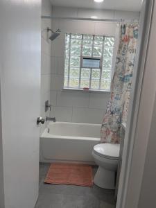 a bathroom with a tub and a toilet and a window at Warm Waters Escape in North Port