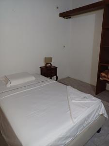 a white bed in a room with a night stand at El Palmar in Palmira