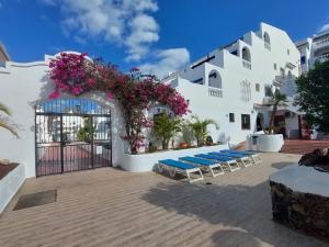 a building with a gate with blue lounge chairs and flowers at Best4Buck in Los Cristianos