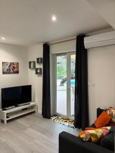 a living room with a tv and a sliding glass door at La Cigalière 1 charmant T1 bis avec terrasse dans villa in Solliès-Ville