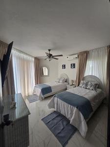 Un dormitorio con dos camas y un ventilador de techo. en Apartamento Playa Juan dolio, en Villas del Mar