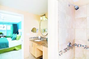 a bathroom with a sink and a shower and a bedroom at Oyster Bay Beach Resort in Dawn Beach