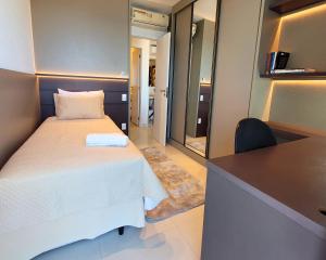 ein Schlafzimmer mit einem Bett und einem Schreibtisch mit Spiegel in der Unterkunft BookSantos Unlimited 2506 Paraíso Vista Mar 2dor in Santos + 37 Fotos