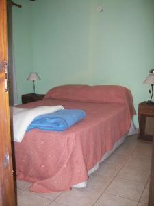 ein Schlafzimmer mit einem Bett mit einer roten Decke in der Unterkunft La casita de Loly in Carilo