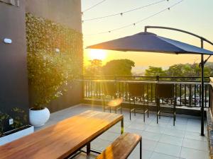 a patio with a wooden bench and an umbrella at FlyNow Studios - Aeroporto Sp Expo Metrô in Sao Paulo