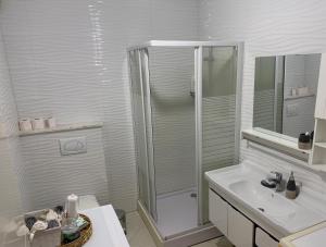 a white bathroom with a shower and a sink at 7 Studio Apartment in Pristina +9 photos