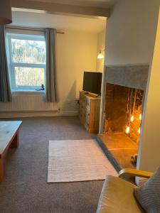 a living room with a fireplace and a television at Willden Cottage in Holmfirth