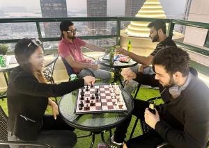 a group of people sitting around a table playing chess at Familiar Partition Room In Tecom Near ICM Metro in Dubai
