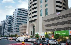 a busy city street with cars parked in front of a building at Familiar Partition Room In Tecom Near ICM Metro in Dubai