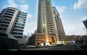 two tall buildings with cars parked in a city at Familiar Partition Room In Tecom Near ICM Metro in Dubai