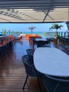una terrazza con tavoli, sedie e l'oceano di Setai Edition - Luxo e Vista para o Mar a João Pessoa